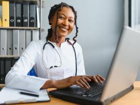 Smiling African American physician typing on laptop computer