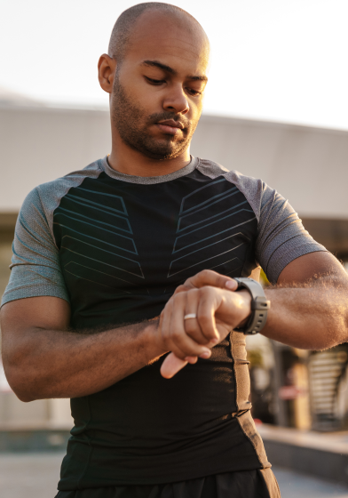 A man looks at his exercise watch while outside.