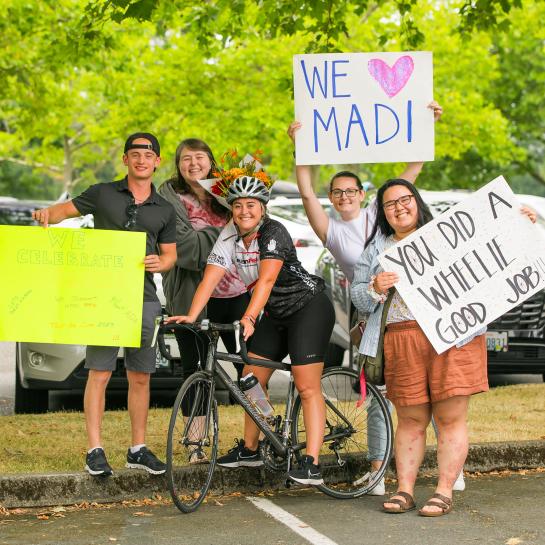 Smiling group holding signs of support for tour de cure bike rider