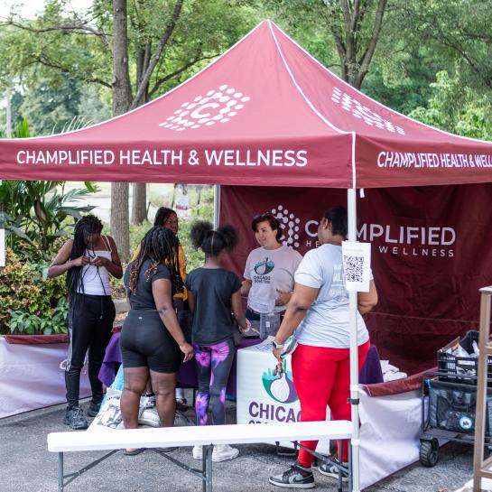 People gathered at Champlified Health and Wellness community event tent