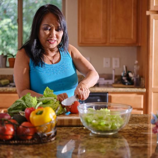 Senior Asian American woman cutting vegetables in kitchen