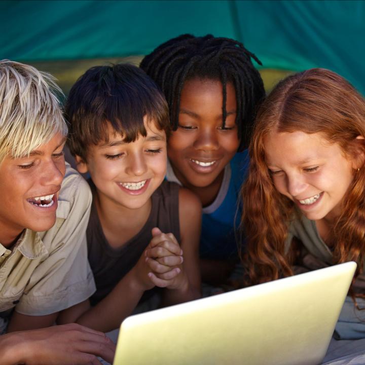 Kids in tent looking at laptop computer