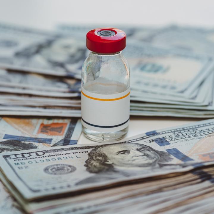 insulin vial next to stacks of 100 dollar bills