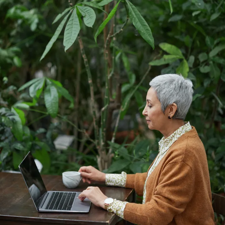 Senior woman taking diabetes risk test on laptop ad desk in garden