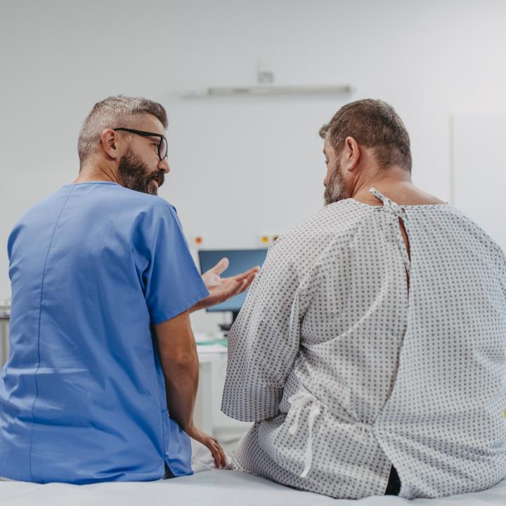 Supportive male physician talking to overweight man in examination room