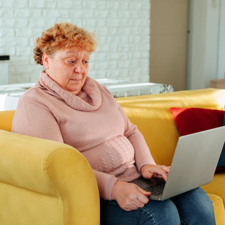 Senior obese woman with surprised look on face looking at laptop computer