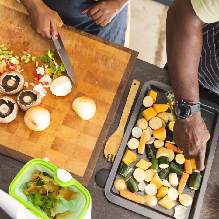 Senior African American couple in kitchen preparing roasted vegetables
