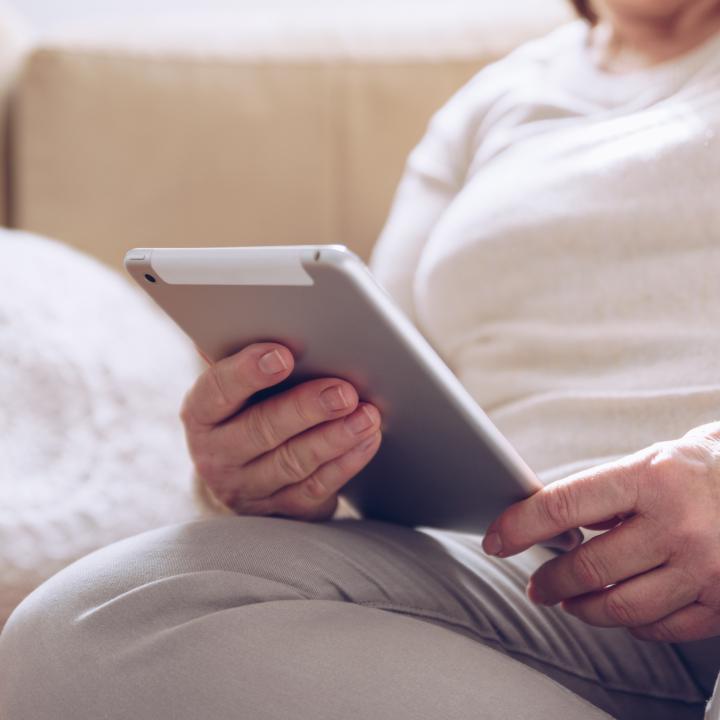Senior woman on couch looking at tablet computer