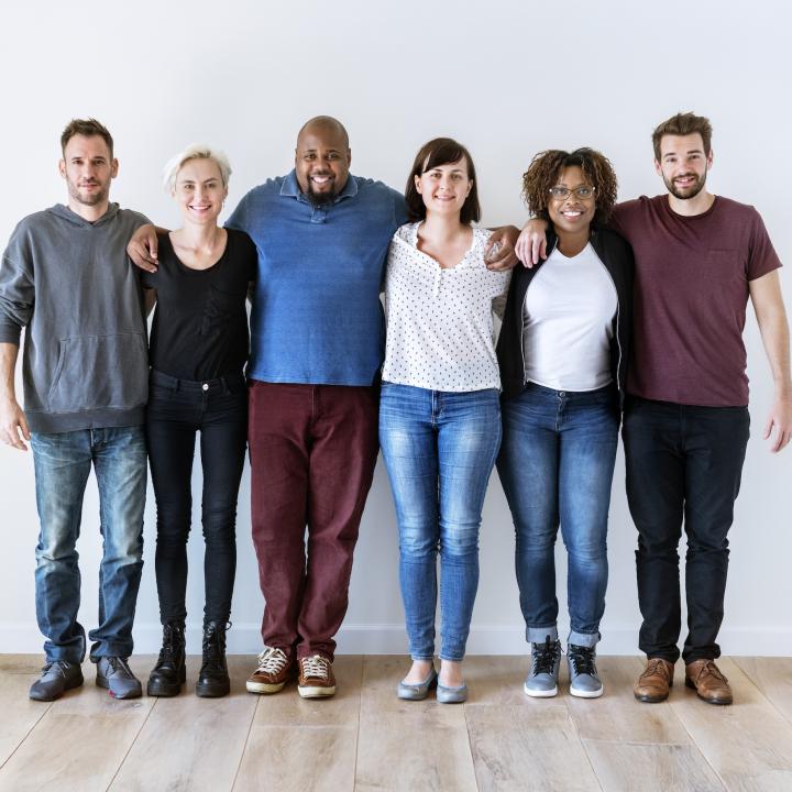 Happy diverse group of friends standing together against a white wall