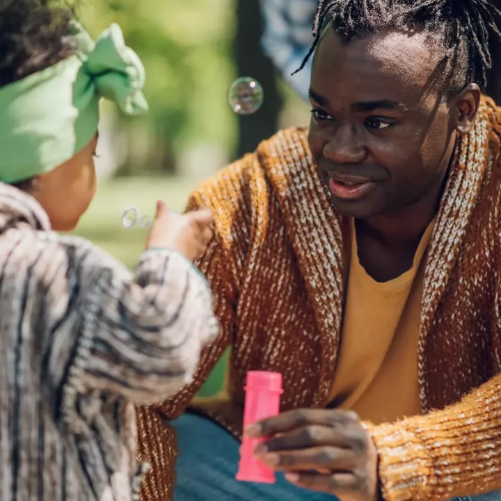 Father blowing bubbles with young daughter