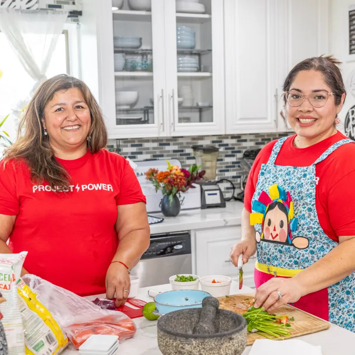 Two women in a kitchen preparing food.