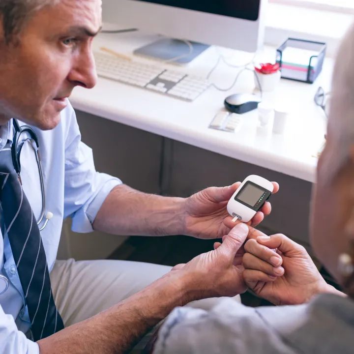 Doctor checks an older woman's blood sugar with a glucose meter.
