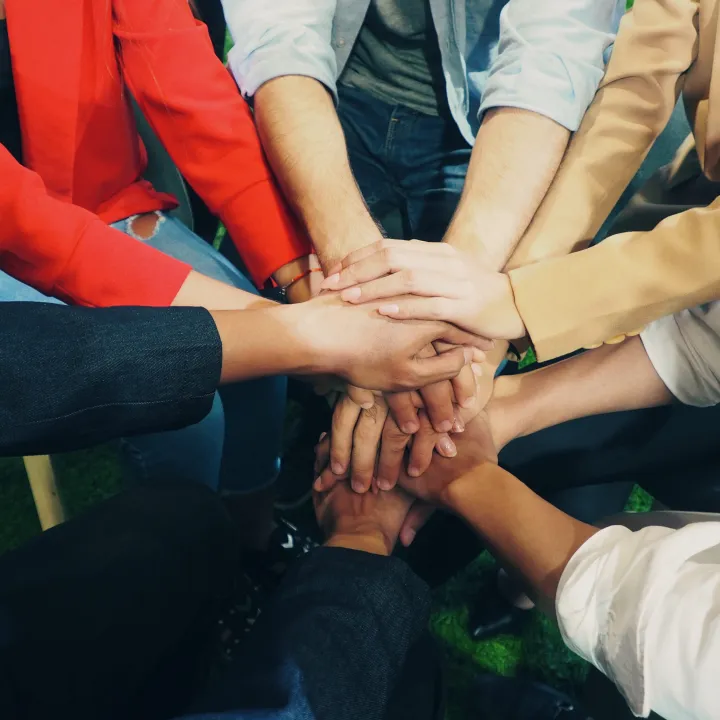 Diverse hands stacked together, symbolizing unity and support.