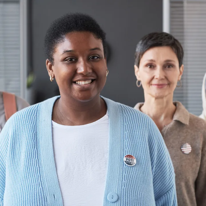 Diverse group of four smiling adults, wearing small pins.