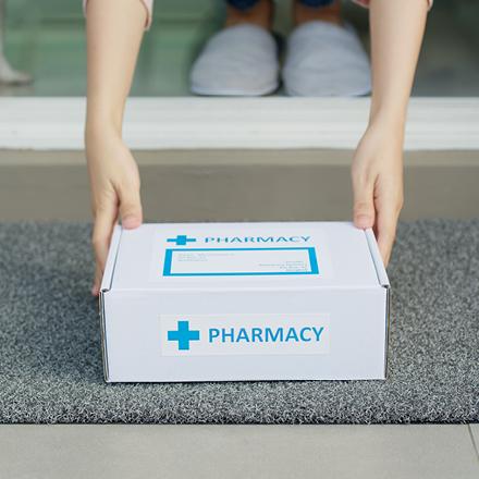 Woman picking up delivered box containing pharmacy items