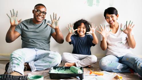 Happy family painting room with paint on their hands