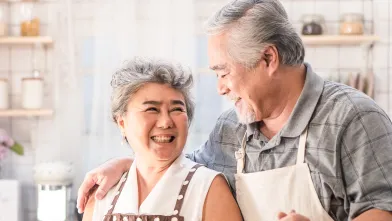 Happy senior couple preparing salad in kitchen