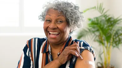 woman smiling with a band-aid on arm