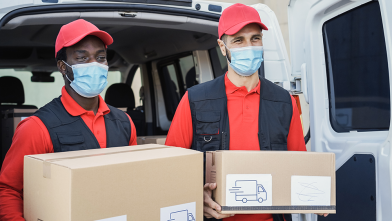 multiracial workers delivering boxes while wearing mask