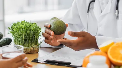 Nutritionist holding avocado discussing health benefits with client