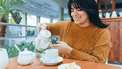 Smiling Latina woman pouring water for tea