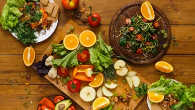 Wooden table served with cut fruits and vegetables