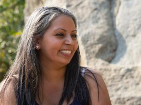 Smiling Hispanic woman outside next to rocks