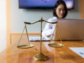 Attorney at laptop behind brass scales of justice