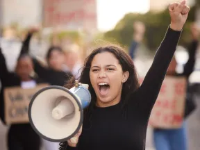 Young defiant Latina with raised fist and megaphone