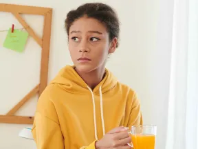 Sad teenage girl holding glass of orange juice