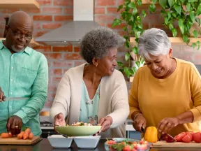 Happy group of racially diverse senior men and women preparing food in kitchen