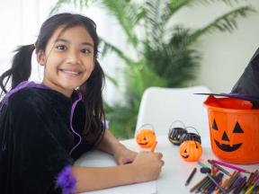 Happy Asian girl writing halloween cards