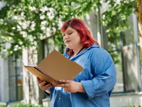 Heavy young woman reading a file outdoors on a sunny day