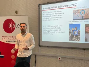 A man presenting in front of a screen about young leaders in diabetes.