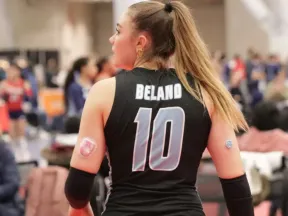 Volleyball player in black jersey, number 10, with diabetes devices on both arms.