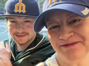 Photograph: Smiling woman and young man wearing Seattle Mariners baseball caps.
