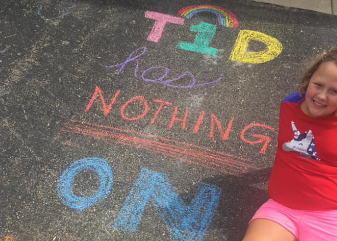 Girl in red shirt on asphalt with colored chalk writing