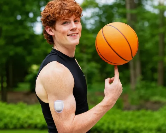 Young man spinning a basketball on his finger with an insulin pump on his arm