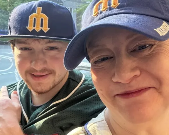 Photograph: Smiling woman and young man wearing Seattle Mariners baseball caps.