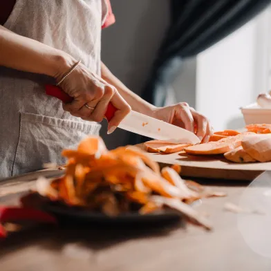 Young woman cutting sweet potato while cooking