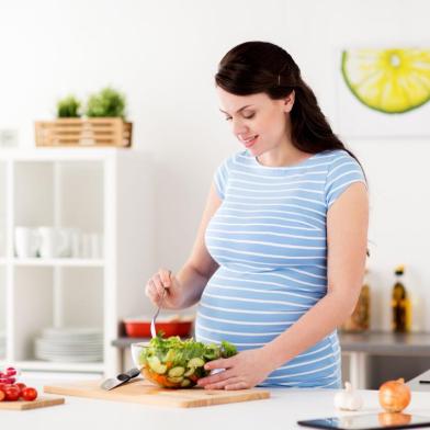 Smiling pregnant woman eating salad