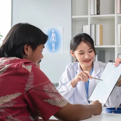 Female doctor explains a document to a smiling male patient in an office.