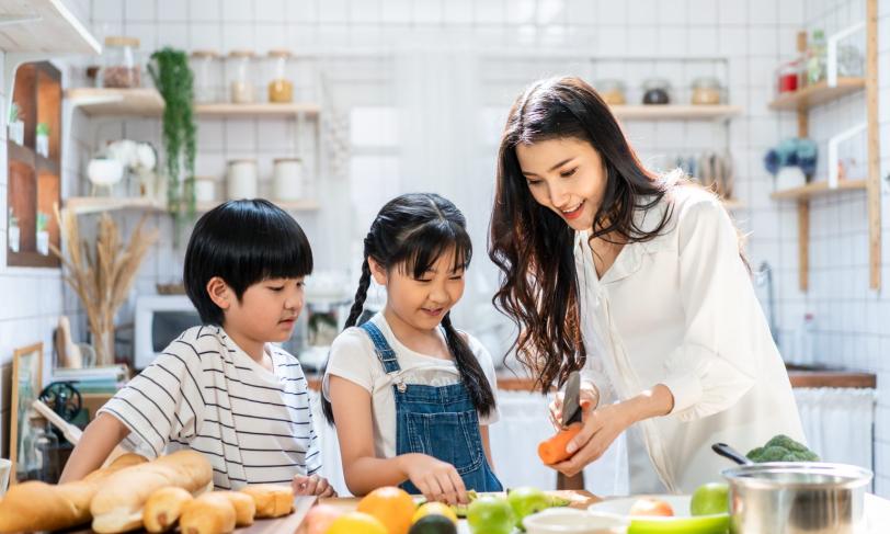 mother and children cutting vegetables in kitchen