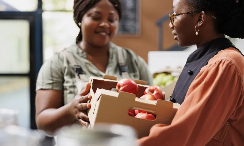 African American women in produce section of market looking at apples