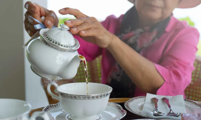 Senior Asian woman pouring tea into cup