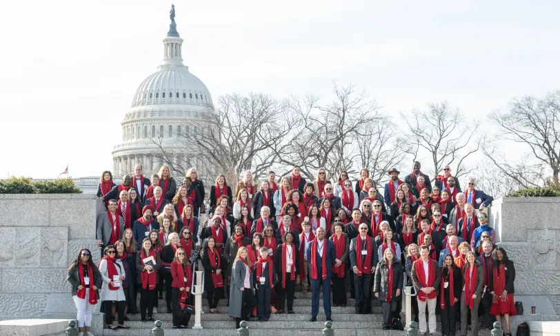 A large group of people stand in front of the United States Capitol building.
