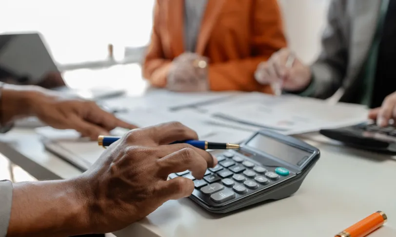 Close up on hands using calculator and writing on a table during a meeting