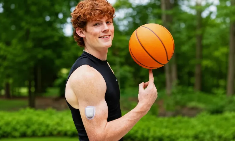 Young man spinning a basketball on his finger with an insulin pump on his arm