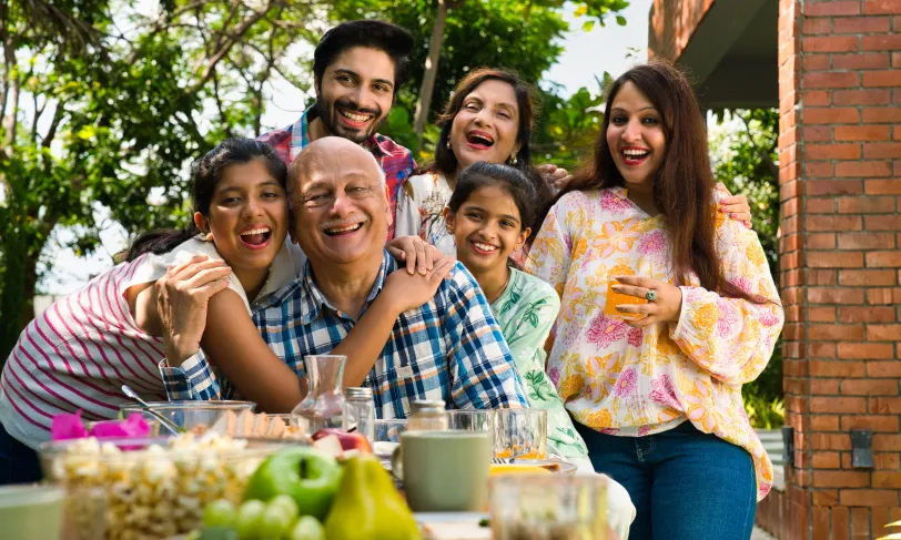 Happy multi-generational Hispanic family outdoors, smiling and laughing at a meal with fruits.