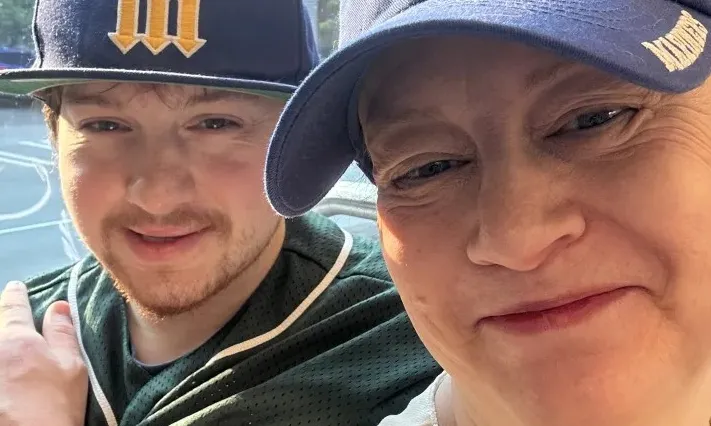 Photograph: Smiling woman and young man wearing Seattle Mariners baseball caps.